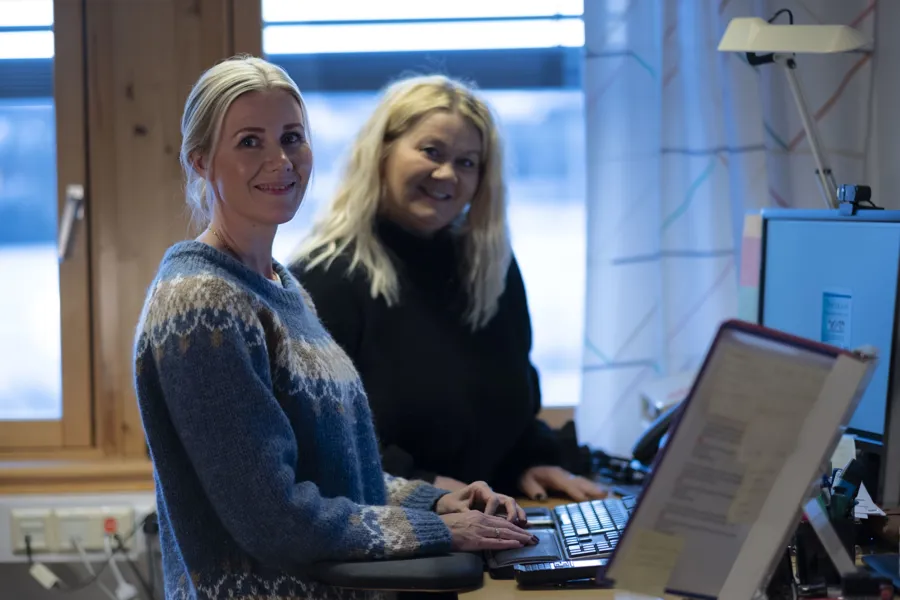 Kvinner som sitter ved et skrivebord med en bærbar datamaskin